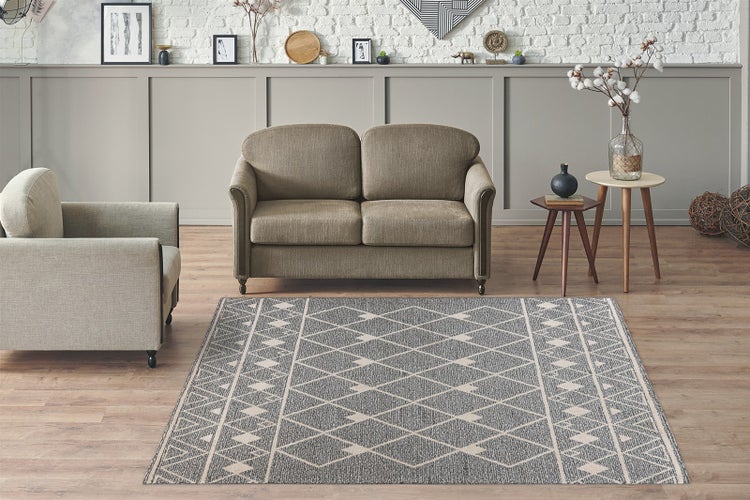 Detailní záběr na šedo-béžový koberec se smyčkovým vlasem a geometrickým vzorem.