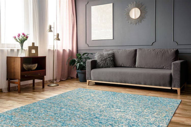Moderní obývací pokoj s modrým vzorovaným kobercem na dřevěné podlaze, šedou pohovkou, růžovými závěsy a dekorativními nástěnnými lištami.