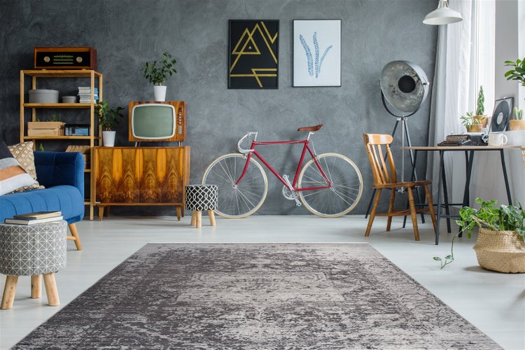 Šedý koberec s krátkým vlasem a vintage vzorem v moderně zařízeném obývacím pokoji s retro nábytkem a jízdním kolem.