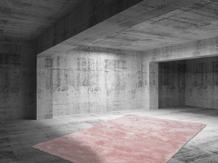 Obdélníkový růžový koberec s dlouhým vlasem na šedé betonové podlaze v moderní místnosti v industriálním stylu.