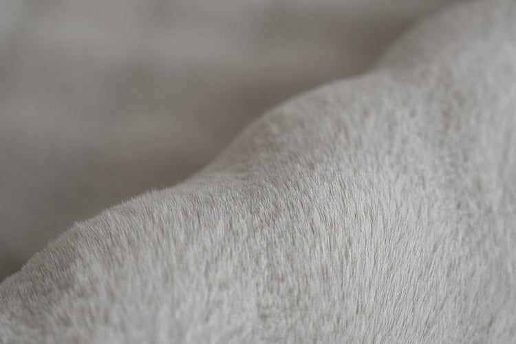 Detail textury měkké plyšové látky nebo umělé kožešiny.