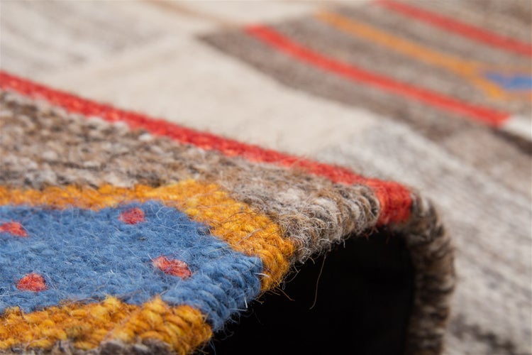 Detailní pohled na strukturu ručně tkaného koberce s vícebarevným geometrickým vzorem.
