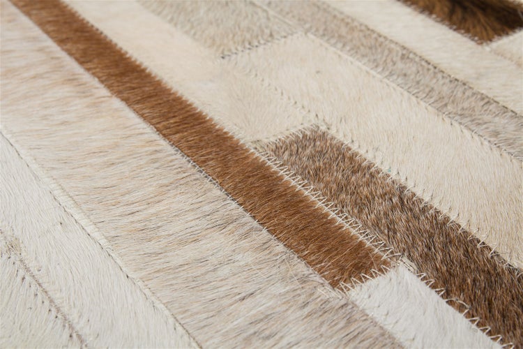 Patchworkový koberec z kousků kůže s viditelnými klikatými švy v obdélníkovém designu.