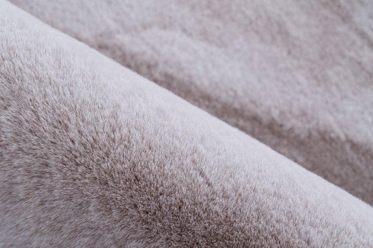 Detailní záběr na měkký béžový koberec z umělé kožešiny s hustou strukturou vláken.