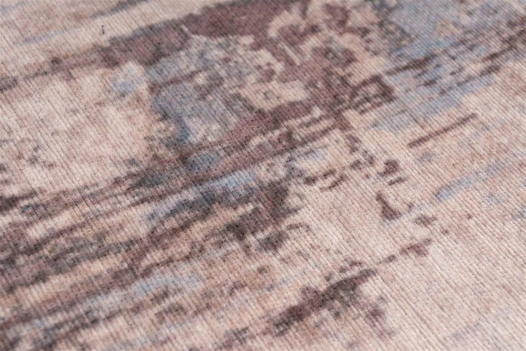 Detail tkaného koberce s abstraktním vintage vzorem a viditelnou povrchovou strukturou.