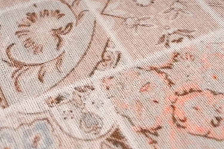 Detailní záběr koberce s vintage patchworkovým vzorem, květinovými ornamenty a žebrovanou tkanou strukturou.