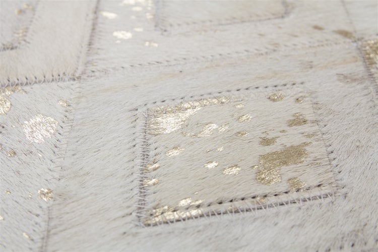 Detail patchworkového koberce z kůže s metalickým efektem a ozdobným prošitím.