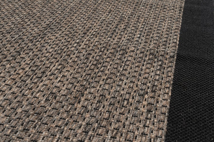 Detailní pohled na tkaný koberec s kostkovaným vzorem a tmavým okrajem.