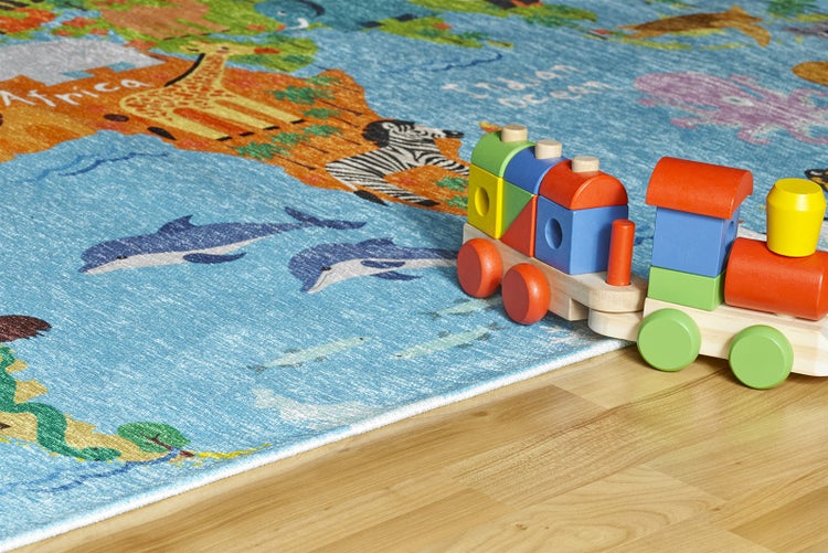 Dětský koberec s mapou světa a motivy zvířat, dřevěný vláček na světlé dřevěné podlaze.