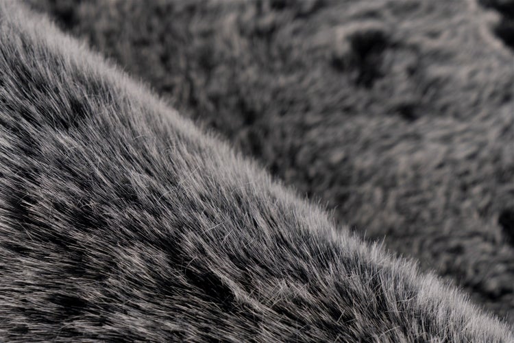 Detailní záběr na nadýchaný šedý koberec z umělé kožešiny s dlouhým vlasem.