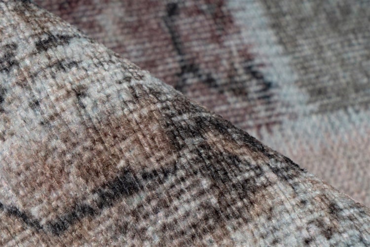 Detailní záběr tkaného koberce se vzorem, zobrazující strukturu povrchu.