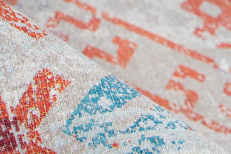 Detailní záběr na koberec s geometrickým vintage vzorem a viditelnou strukturou tkaní.