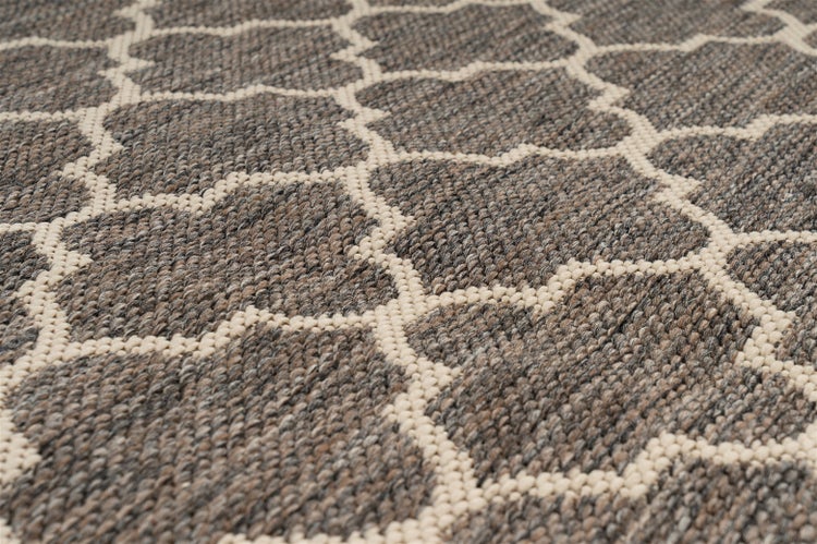 Detail tkaného koberce s geometrickým mřížkovým vzorem v šedé a béžové barvě.