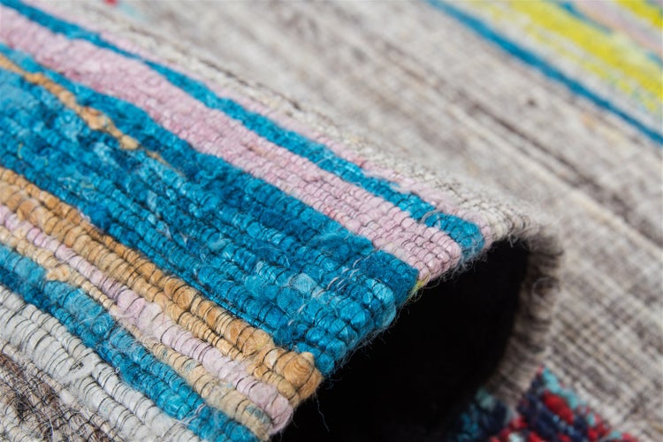 Detailní záběr vícebarevného tkaného koberce s pruhovaným vzorem a hrubou texturou.