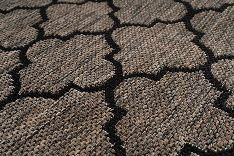 Detail tkaného koberce s geometrickým vzorem a strukturovaným povrchem.