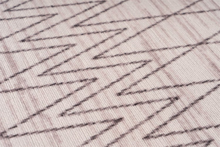 Detail tkaného koberce s klikatým vzorem a žebrovanou strukturou.