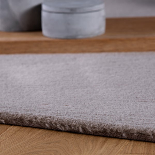 Detailní záběr na měkký, huňatý koberec z umělé kožešiny na dřevěné podlaze, který ukazuje jeho hustou texturu.