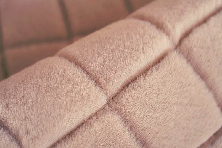 Detailní pohled na prošívanou umělou kožešinu s obdélníkovým polstrováním a měkkou strukturou.