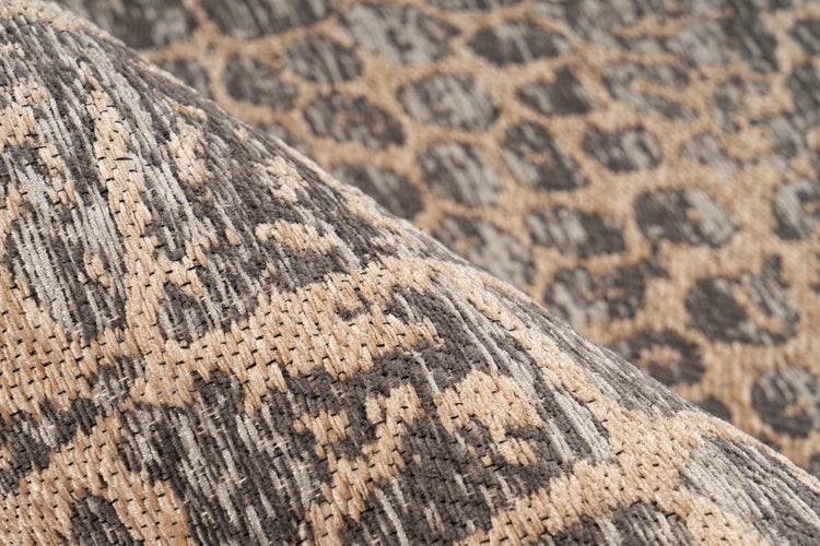 Detailní záběr na tkaný koberec s leopardím vzorem v hnědé a béžové barvě, zobrazující detailní texturu a strukturu vláken.