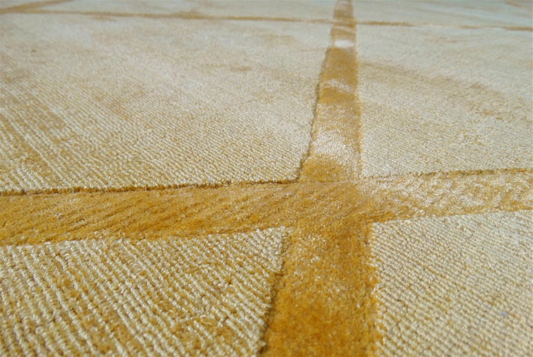 Detailní záběr žlutého koberce s geometrickým vzorem linií a strukturovaným, hustým vlasem.