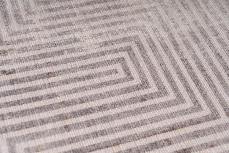 Detail tkaného koberce s geometrickým vzorem soustředných linií.