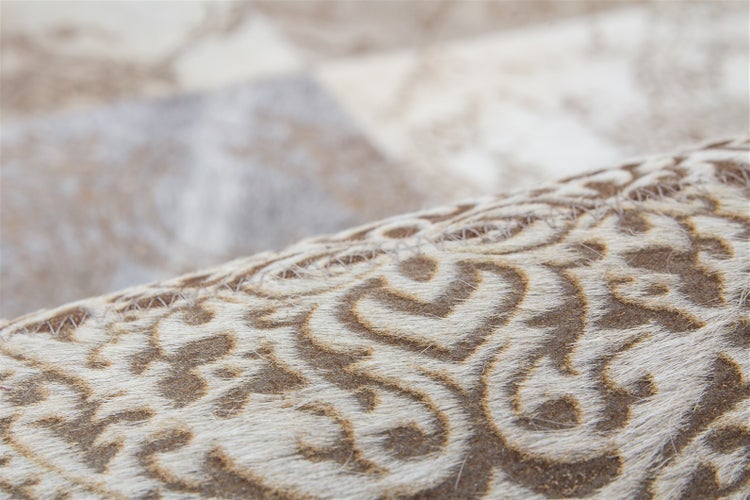 Detailní záběr patchworkového koberce z hovězí kůže s ornamentálním vzorem.