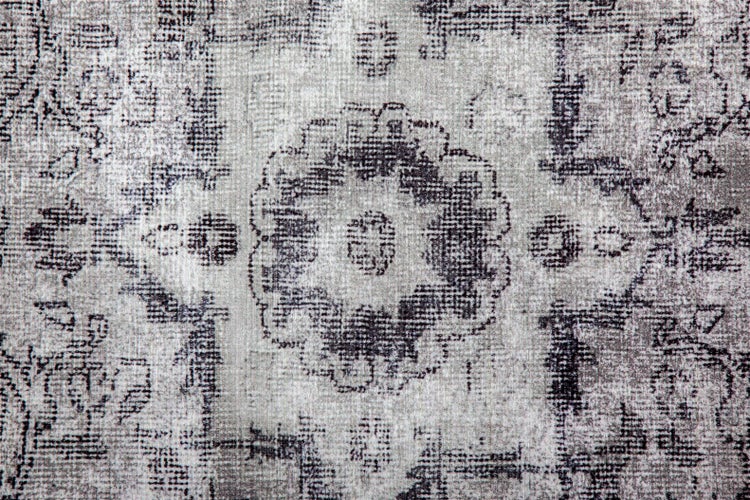 Detailní záběr koberce ve vintage stylu s opotřebovaným vzorem medailonu.
