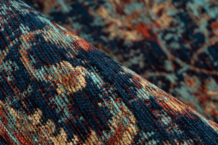Detailní záběr na tkaný koberec s vintage vzorem v modré a oranžové barvě.