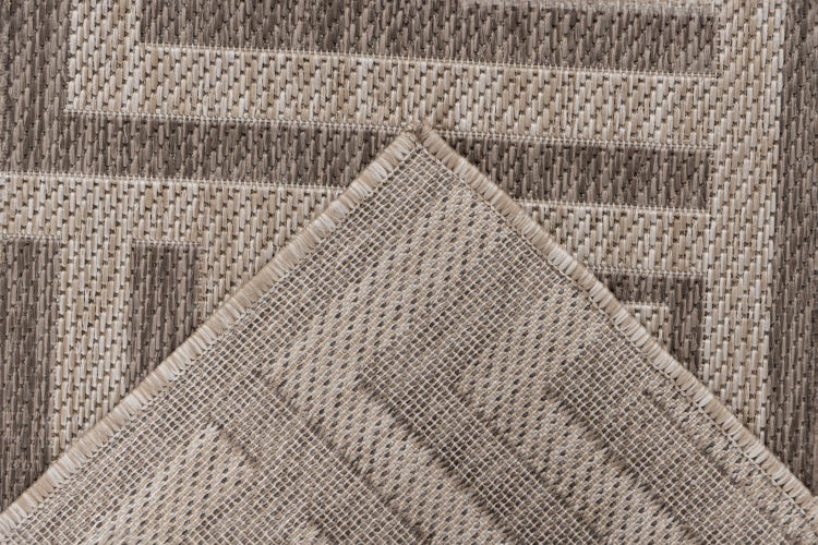Detailní záběr tkaného koberce s geometrickým vzorem a obšitým okrajem.