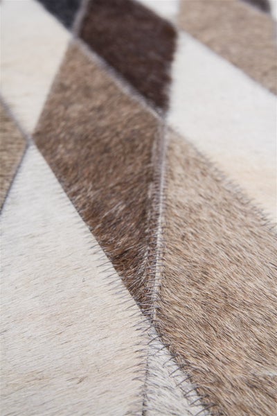 Detailní pohled na patchworkový koberec z kousků hovězí kůže s viditelným cikcak švem.