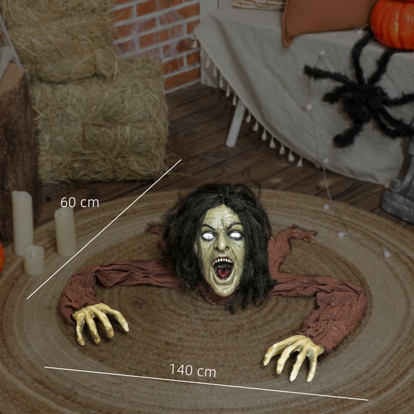 Halloweenská dekorace s figurkou zombie na koberci, obklopená balíky sena a svíčkami.