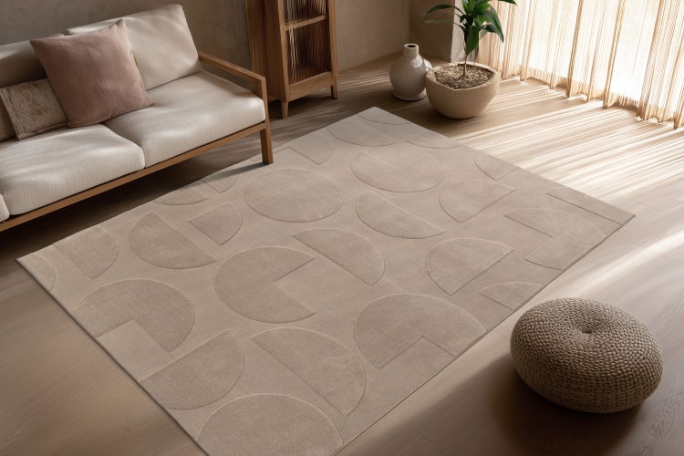 Obývací pokoj s obdélníkovým kobercem s geometrickým vzorem půlkruhů na dřevěné podlaze před pohovkou s dřevěnými prvky a pokojovou rostlinou