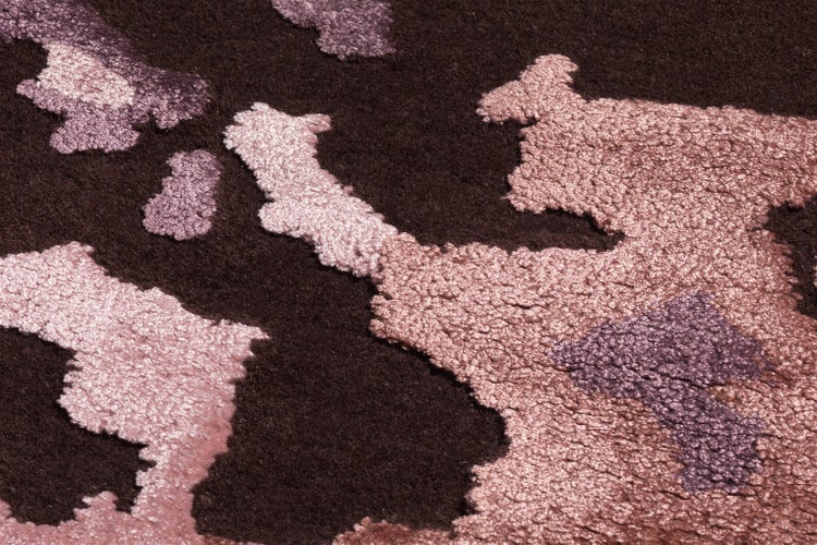 Koberec s abstraktním vzorem a texturovaným povrchem v detailu.
