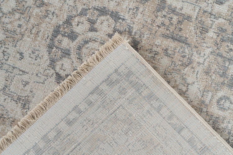Detailní pohled na koberec s vintage vzorem, třásněmi a viditelnou tkanou spodní stranou.