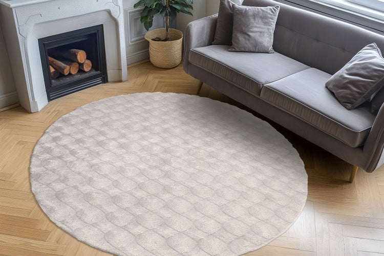 Kulatý koberec s texturovaným povrchem v elegantně zařízeném obývacím pokoji s krbem a pohovkou na parketové podlaze.