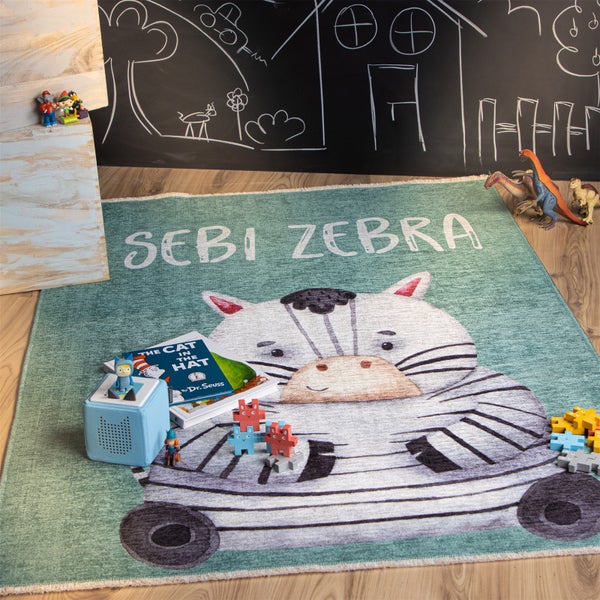 Dětský koberec s motivem zebry a nápisem Sebi Zebra leží na podlaze a je obklopen hračkami.