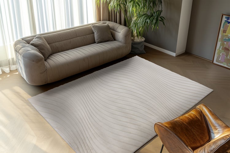 Obývací pokoj s moderní pohovkou a obdélníkovým kobercem s vlnitým vzorem na parketové podlaze.
