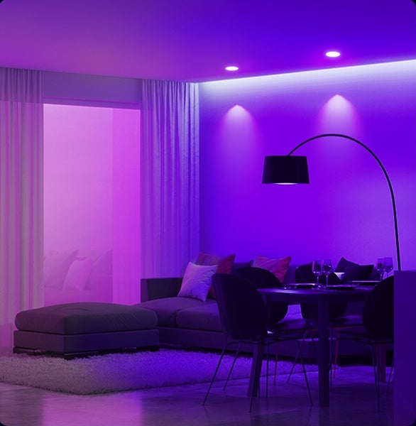 Obývací pokoj s moderním LED osvětlením ve fialové barvě. Pohovka, jídelní stůl se židlemi a oblouková lampa vytvářejí stylovou atmosféru.