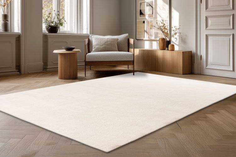 Světle barevný obývací koberec v moderním interiéru s parketovou podlahou, křeslem a dřevěným nábytkem.