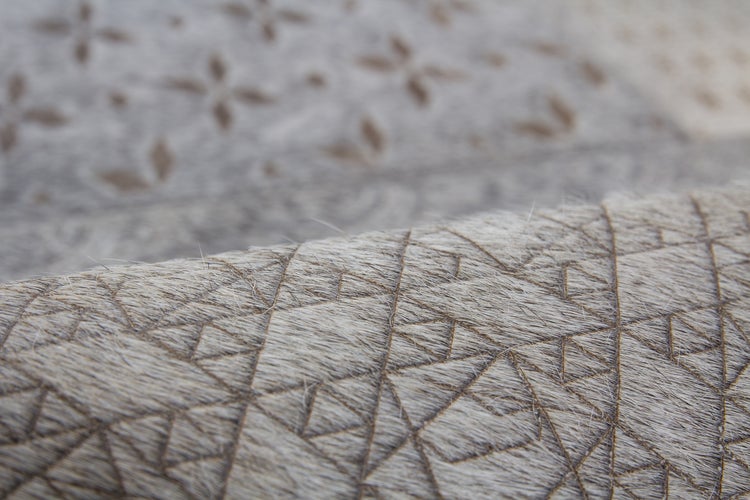 Detailní záběr kožešinového koberce s geometrickým vzorem trojúhelníků.