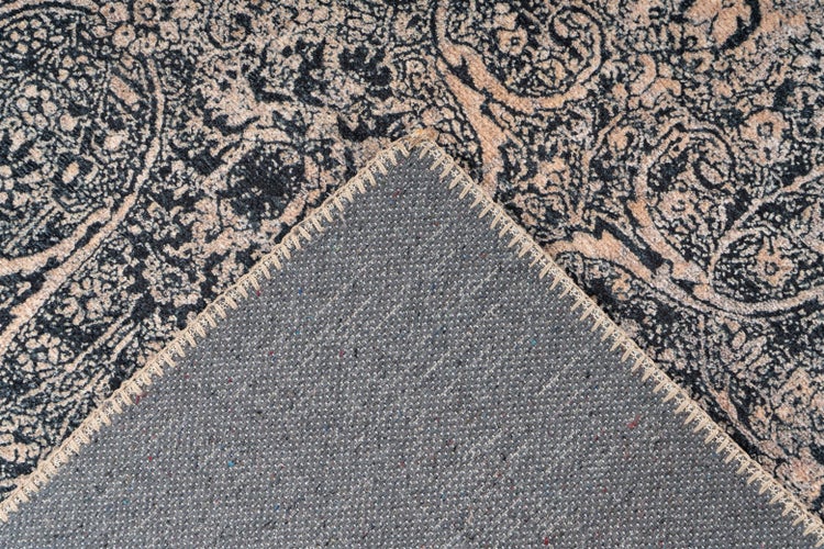 Detail koberce s vintage vzorem, který ukazuje strukturovanou spodní stranu a obšitý okraj.