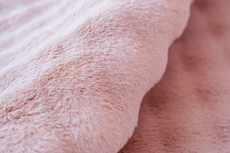 Detailní záběr na měkkou růžovou umělou kožešinu s huňatou texturou.