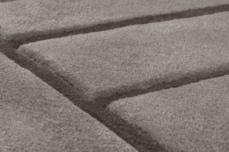 Detail koberce s geometrickým vzorem linií a strukturovaným povrchem