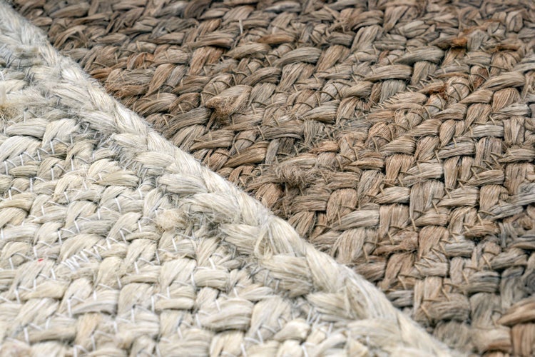 Detail ručně tkaného jutového koberce s hrubou strukturou.