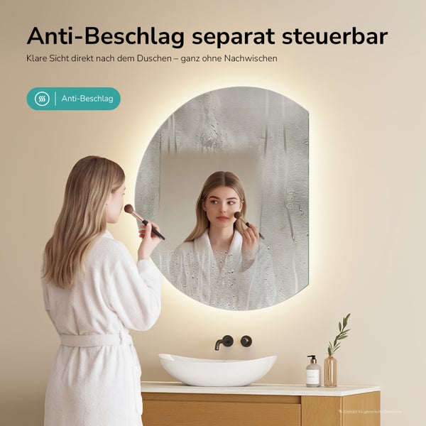 Půlkruhové LED zrcadlo se samostatně ovládaným odmlžováním. Žena si nanáší make-up před koupelnovým zrcadlem, které má jasné zorné pole.
