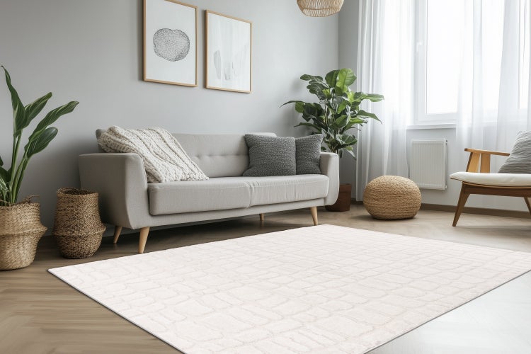 Obývací pokoj s obdélníkovým kobercem s geometrickým vzorem na dřevěné podlaze, doplněný pohovkou, křeslem a dekoracemi.