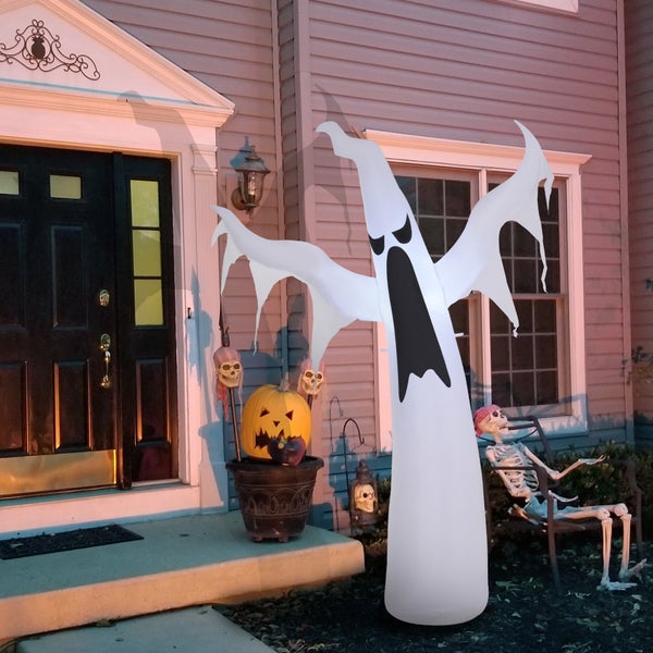 Halloweenská dekorace s nafukovací příšerou, dýní, kostrami a lebkami před domem.