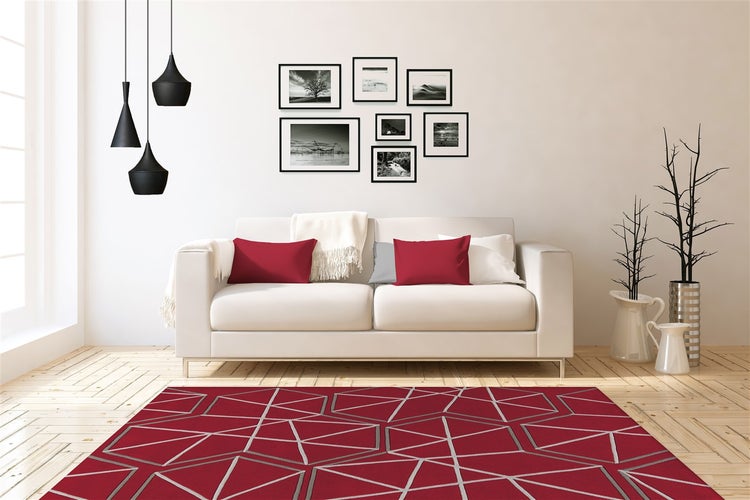 Obývací pokoj s pohovkou, polštáři a kobercem s geometrickým vzorem na parketové podlaze v moderně zařízeném interiéru.