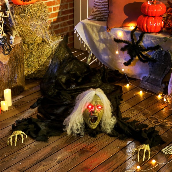 Dekorativní halloweenská scéna s figurkou čarodějnice, balíky slámy, dýněmi a náhrobkem