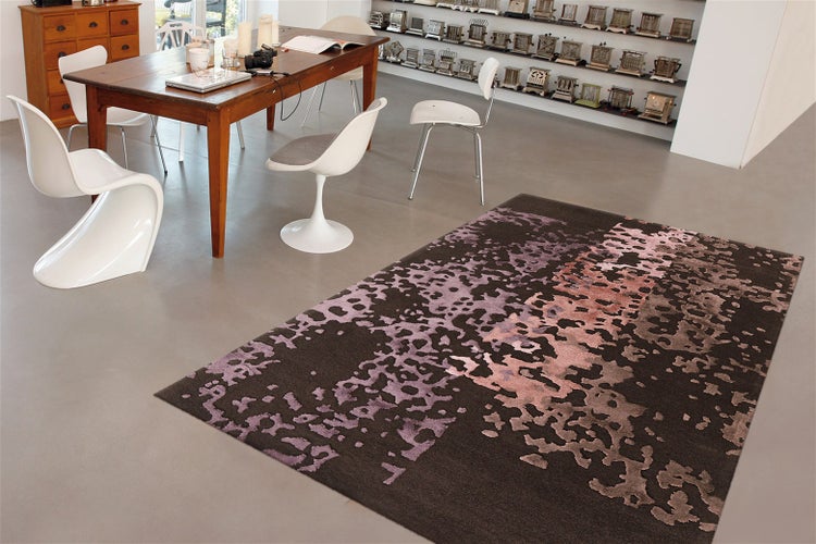 Moderní bytový koberec s abstraktním vzorem v jídelně s dřevěným stolem a designovými židlemi na hladké podlaze.